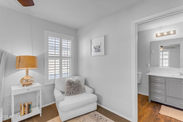 living area with dark wood-type flooring, sink, and ceiling fan