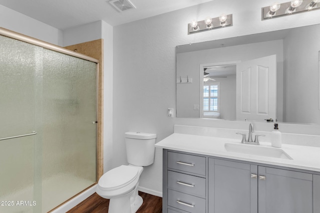 bathroom with a shower with door, vanity, hardwood / wood-style floors, and toilet