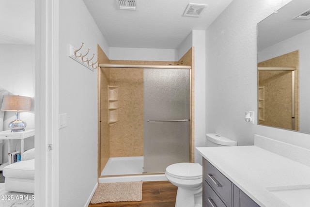 bathroom featuring an enclosed shower, vanity, hardwood / wood-style flooring, and toilet