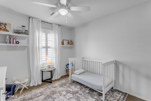 bedroom featuring a nursery area and ceiling fan