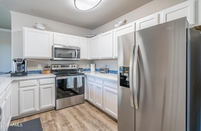 kitchen featuring light wood finished floors, white cabinetry, stainless steel appliances, and light countertops