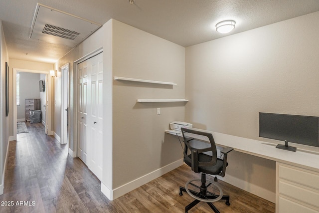 home office with built in desk, wood finished floors, visible vents, and baseboards