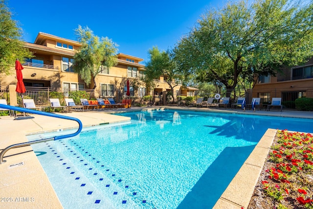 community pool featuring a patio area, fence, and a water slide