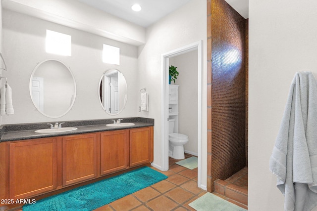 bathroom featuring tile patterned flooring, double vanity, a tile shower, and a sink