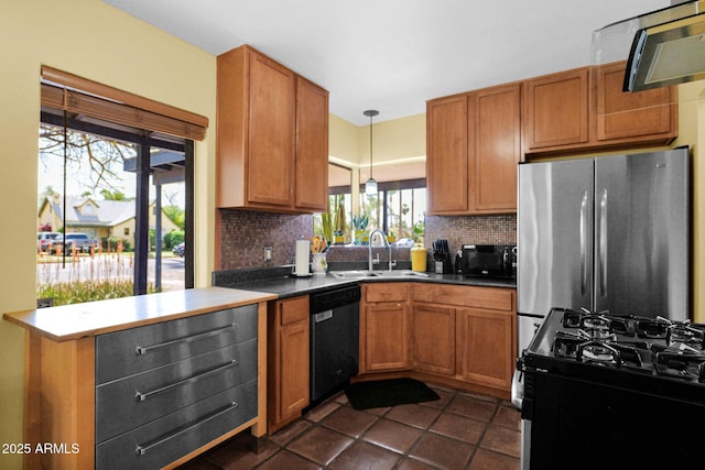 kitchen with freestanding refrigerator, a sink, decorative backsplash, black dishwasher, and range with gas cooktop