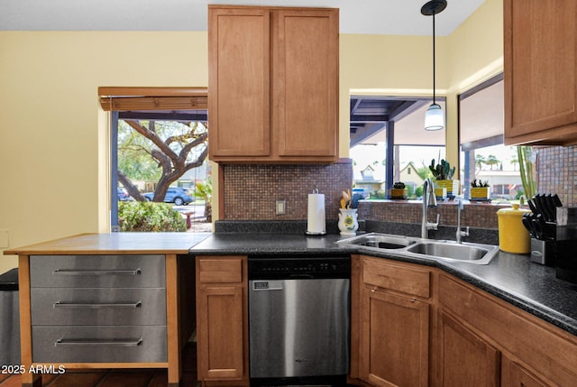 kitchen with dark countertops, tasteful backsplash, decorative light fixtures, stainless steel dishwasher, and a sink