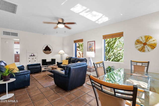 living room with visible vents, ceiling fan, and dark tile patterned flooring