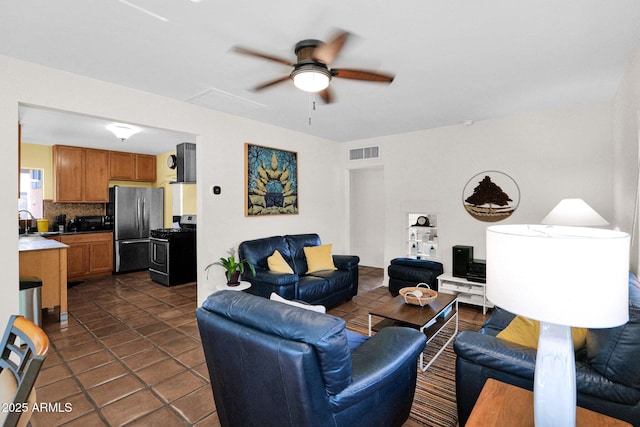 living room featuring dark tile patterned floors, visible vents, and ceiling fan