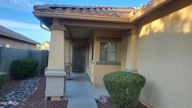 3347 W Steinbeck Dr, Anthem, AZ 85086 - view of exterior entry with stucco siding, a tiled roof, and fence
