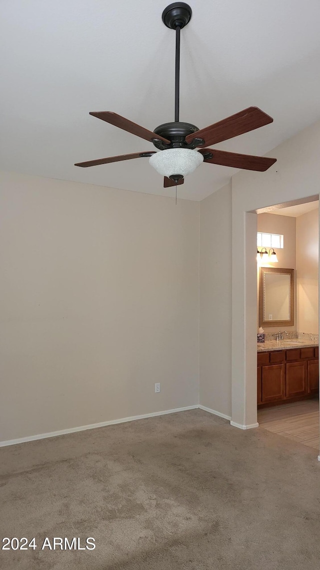 spare room with sink, light carpet, and ceiling fan