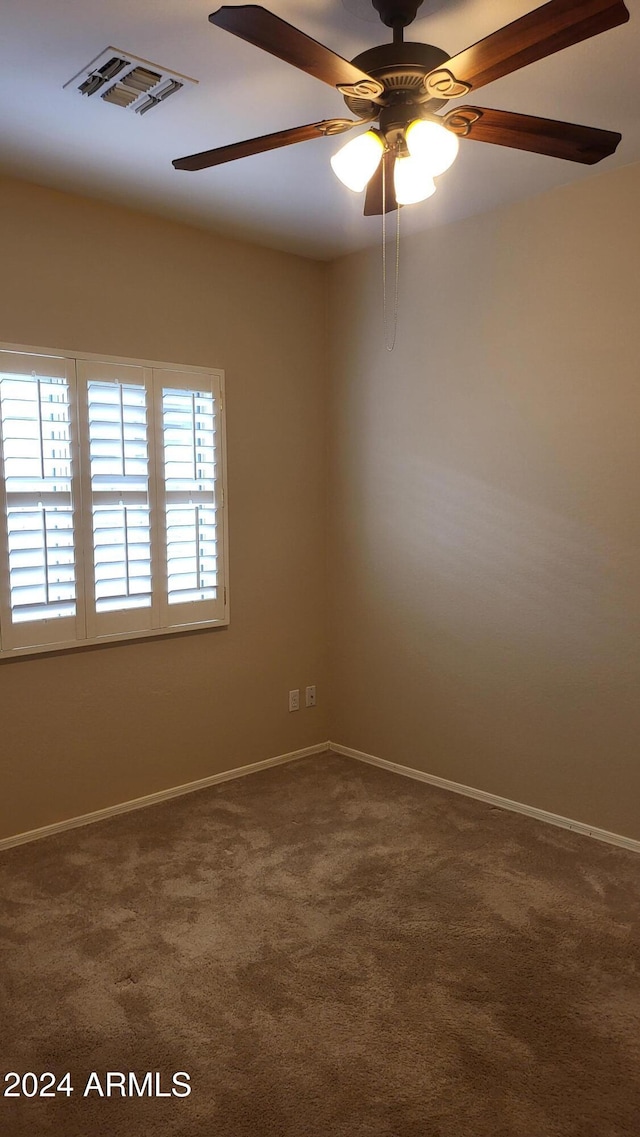 empty room featuring ceiling fan and dark colored carpet