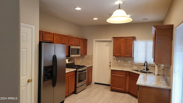 kitchen featuring hanging light fixtures, sink, light stone countertops, appliances with stainless steel finishes, and tasteful backsplash