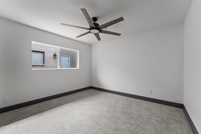 carpeted spare room featuring a ceiling fan and baseboards