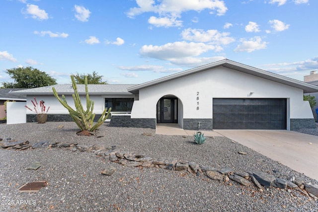 view of front facade featuring stone siding, stucco siding, an attached garage, and concrete driveway