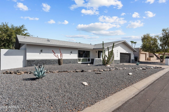 ranch-style home with stucco siding, stone siding, concrete driveway, and an attached garage