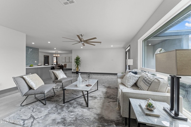 living room with recessed lighting, visible vents, baseboards, and ceiling fan with notable chandelier