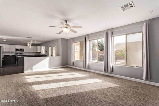 unfurnished living room with carpet flooring and ceiling fan with notable chandelier