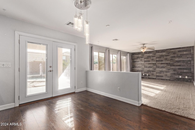 empty room featuring french doors, ceiling fan with notable chandelier, and dark hardwood / wood-style flooring