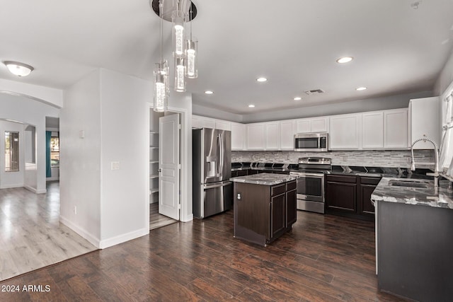 kitchen with light stone counters, stainless steel appliances, a kitchen island, and sink