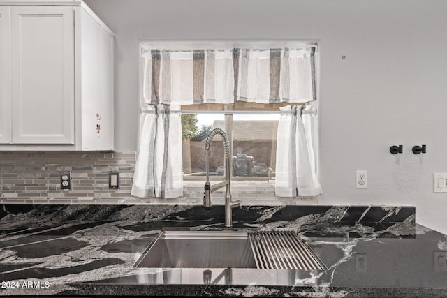 room details with backsplash, dark stone countertops, sink, and white cabinets