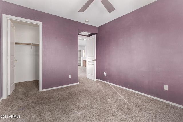 unfurnished bedroom with carpet flooring, ceiling fan, a closet, and a spacious closet