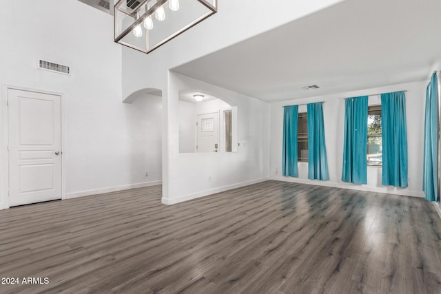 unfurnished living room featuring dark hardwood / wood-style flooring and a chandelier