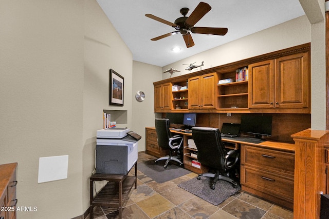 office space with baseboards, stone finish floor, ceiling fan, and built in study area