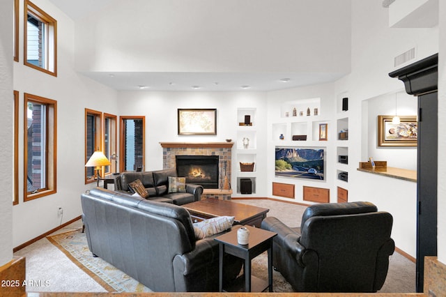 living room with a glass covered fireplace, built in features, carpet, and visible vents