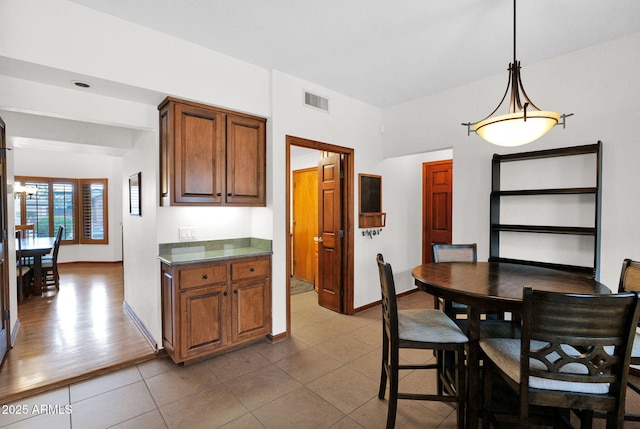 dining room featuring dark tile patterned floors, baseboards, and visible vents