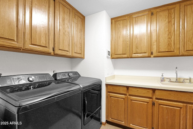 clothes washing area with a sink, cabinet space, and washing machine and clothes dryer