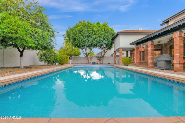 view of swimming pool with a patio area, a fenced backyard, a fenced in pool, and grilling area