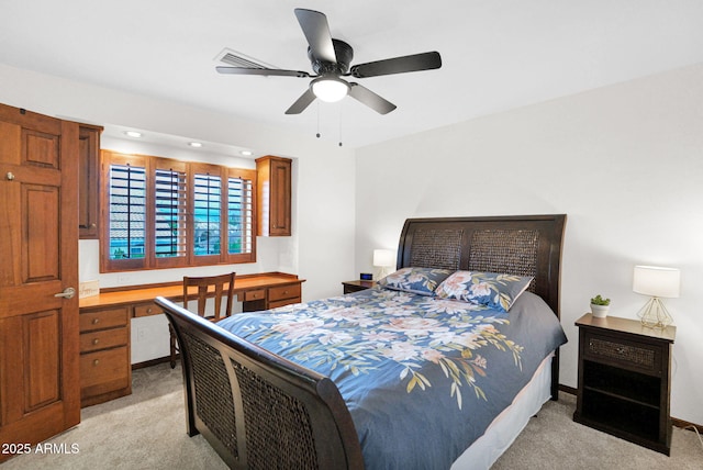 bedroom with light colored carpet, built in study area, and baseboards