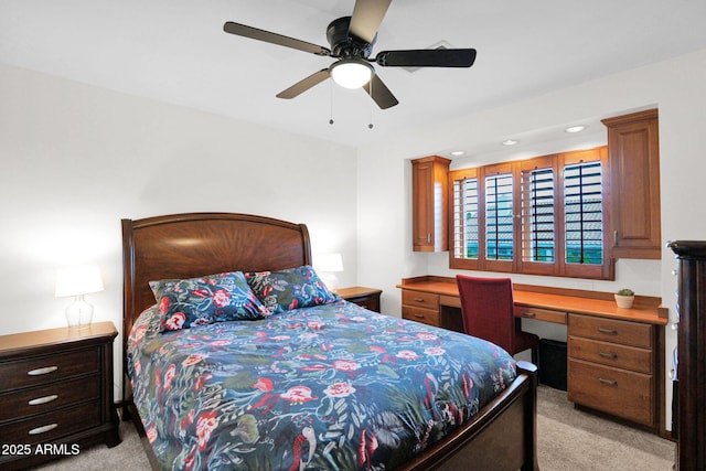 bedroom with ceiling fan, light carpet, and built in study area