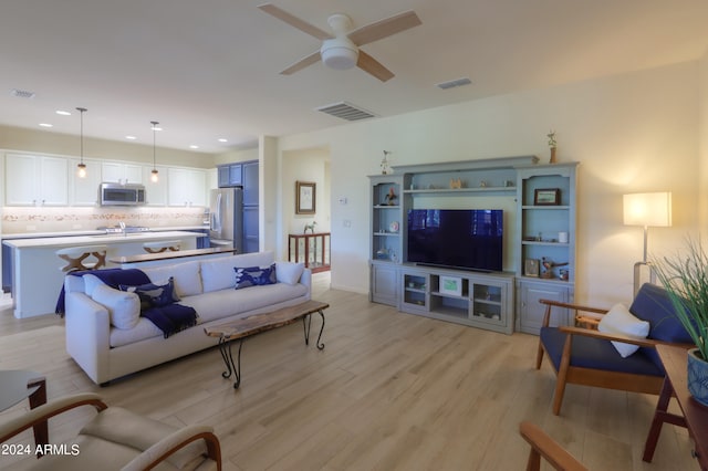 living room featuring light hardwood / wood-style flooring, sink, and ceiling fan