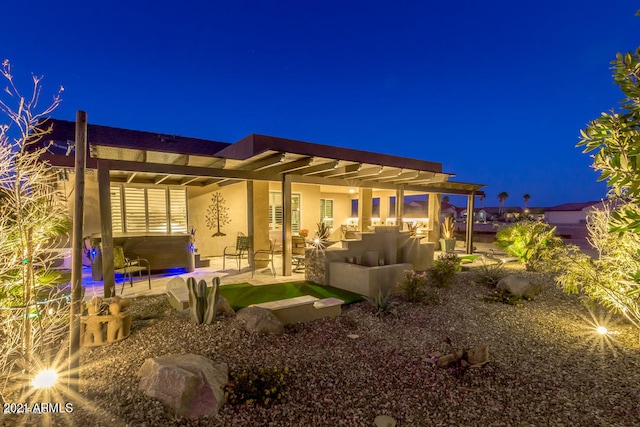 back house at twilight with a patio area and a pergola