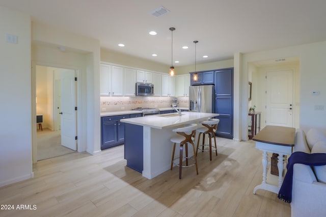 kitchen with decorative light fixtures, backsplash, appliances with stainless steel finishes, blue cabinetry, and light hardwood / wood-style floors