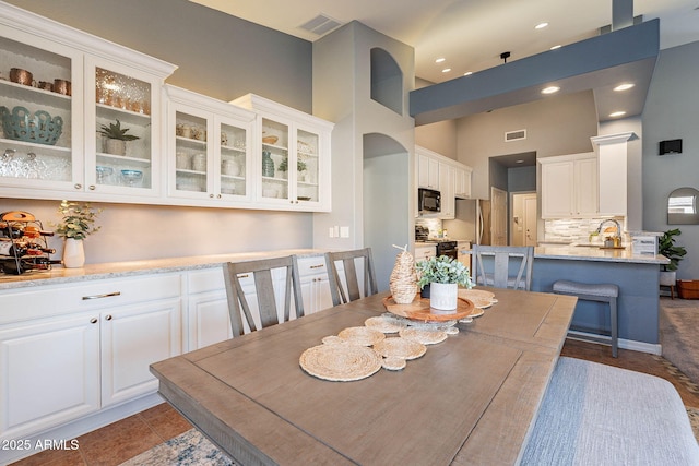 dining room featuring a towering ceiling and dark tile patterned floors