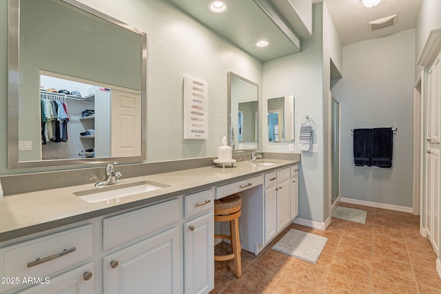 bathroom featuring tile patterned floors, a shower with door, and vanity