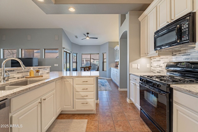 kitchen featuring kitchen peninsula, ceiling fan, black appliances, light stone counters, and sink