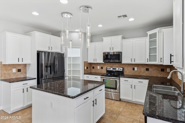 kitchen with white cabinetry, sink, stainless steel appliances, decorative light fixtures, and a kitchen island