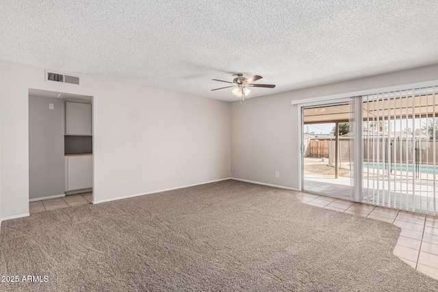 tiled empty room featuring carpet flooring, a ceiling fan, visible vents, and a textured ceiling