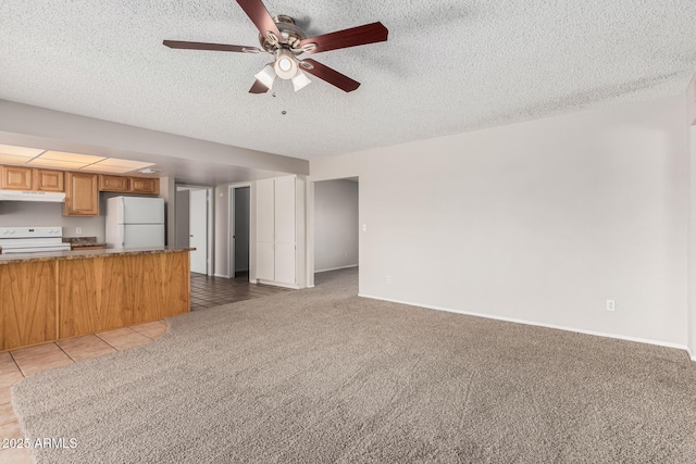 kitchen with white appliances, brown cabinetry, under cabinet range hood, light colored carpet, and open floor plan