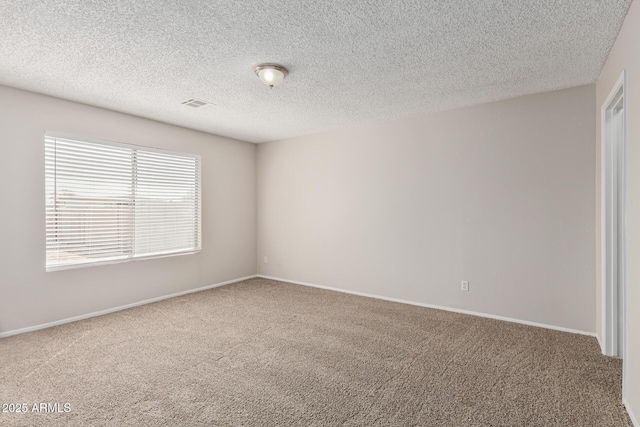 carpeted empty room featuring baseboards, visible vents, and a textured ceiling