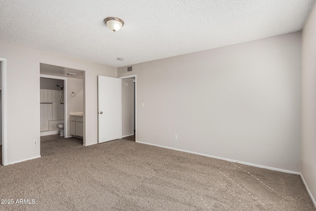 unfurnished bedroom with baseboards, visible vents, carpet floors, ensuite bath, and a textured ceiling