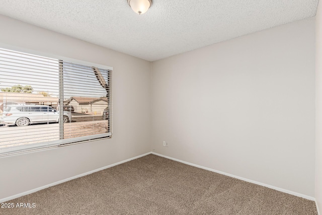 carpeted spare room featuring baseboards and a textured ceiling