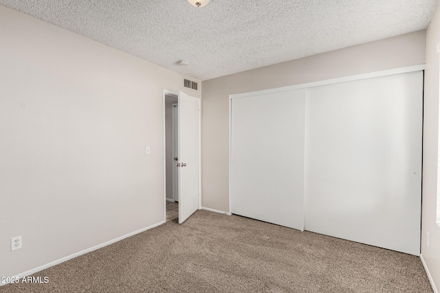 unfurnished bedroom featuring baseboards, visible vents, carpet floors, a closet, and a textured ceiling