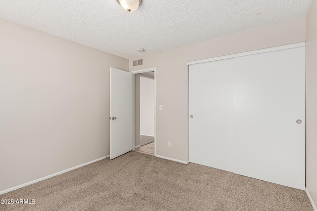 unfurnished bedroom featuring a closet, visible vents, carpet flooring, and a textured ceiling