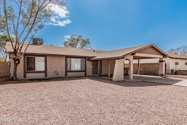 ranch-style home featuring stucco siding, roof with shingles, central AC, and fence