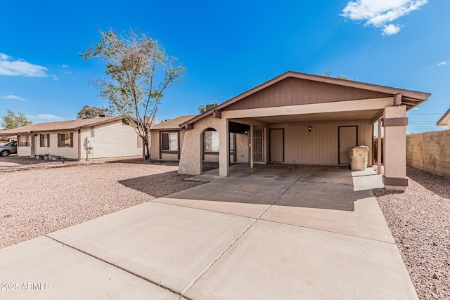 ranch-style house with concrete driveway and fence