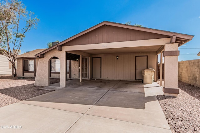 view of front of house featuring a carport, concrete driveway, fence, and roof with shingles